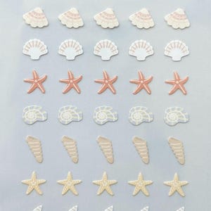 Puede incluir: Una hoja de pegatinas decorativas con diseños de conchas marinas en tonos blanco, melocotón y beige. Las pegatinas incluyen estrellas de mar, conchas y conchas en espiral. El texto "mini series" está escrito en escritura negra.