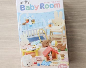 May include: A rectangular Re-Ment Miffy Baby Room toy box featuring a light blue and white color scheme. The packaging displays various miniature nursery furniture items, including a crib, high chair, playhouse, and small animal figurines.