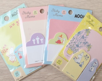 May include: Four sets of Moomin themed sticky memo pads in clear plastic packaging. Each set features colorful paper notes with various character illustrations, including Moomin, Little My, and Snufkin, with text labels reading Sticky Memo and Moomin.