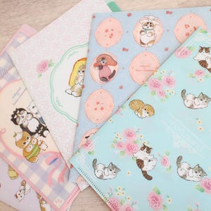 May include: A collection of colorful, patterned folders featuring cute animal illustrations. Designs include cats, dogs, and bunnies, with floral and polka dot backgrounds. The folders are in shades of blue, pink, and white.