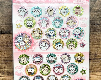 May include: A sheet of stickers featuring various cartoon characters in a variety of poses. The stickers are round with glittery borders and include Japanese text. The packaging is pink and white.