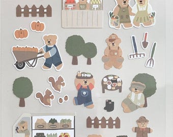May include: Sheet of Daily Deco Stickers featuring a farm theme. The stickers include illustrations of bears, vegetables, farm tools, and the text "DAILY DECO STICKERS" and "ggumi farm". The stickers are in various colors, including brown, green, and orange.