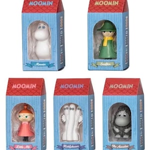 Op de afbeelding: Vijf Moomin-personagebeeldjes in hun originele verpakking. Elk figuur wordt weergegeven in een blauwe doos met een rood dak en het woord "MOOMIN" erboven. De personages zijn onder meer Moomin, Snufkin, Little My, Hattifatteners en The Ancestor.