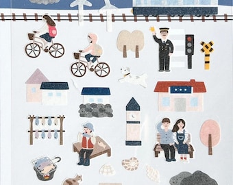 May include: Sheet of Suatelier stickers featuring an ocean village theme. The stickers include illustrations of a lighthouse, boats, trains, people riding bikes, houses, trees, and the word "Fishing".