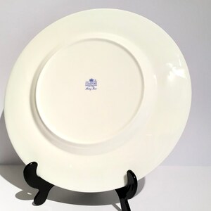 May include: White ceramic dinner plate with a blue and white floral pattern. The back of the plate has a blue stamp that reads "Coalport Fine Bone China Made in England" and "King's Rose".
