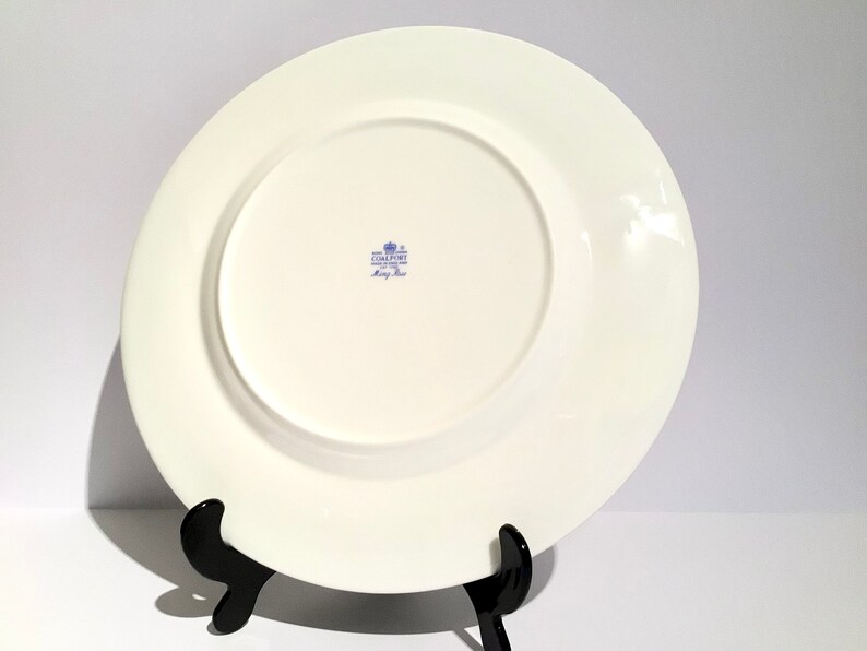 May include: White ceramic dinner plate with a blue and white floral pattern. The back of the plate has a blue stamp that reads "Coalport Fine Bone China Made in England" and "King's Rose".