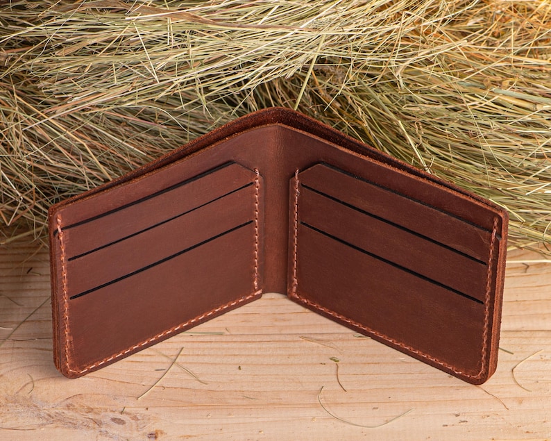 May include: A brown leather wallet with multiple card slots and a billfold. The wallet is open and lying on a wooden surface.