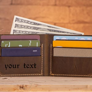 May include: A brown leather wallet with multiple card slots and a cash pocket. The wallet has a personalized inscription that reads "your text".