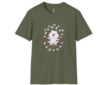 May include: An olive green short-sleeve t-shirt featuring a central graphic of a light-colored wombat with a red nose. The text reads WOMBAT WONTONS, ARTISTIC APPAREL, and THE TRADE MARK, surrounded by small white leaf illustrations in a circular pattern.