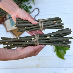Op de afbeelding: Twee bundels natuurlijke, bruine twijgen die met touw aan elkaar zijn gebonden. De twijgen zijn ongeveer 25 cm lang en perfect voor knutselen of decoreren.