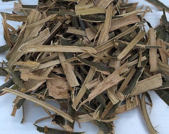 May include: A pile of dried, shredded bark with a mix of light brown and dark green hues. The texture appears rough and splintered, with various sizes and shapes of bark pieces. The image is taken from a close-up perspective, highlighting the natural details.