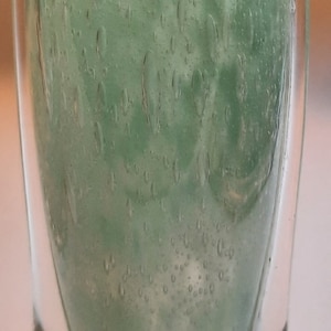 Può includere: Un vaso di vetro verde con una superficie testurizzata e due manici. Il vaso ha una base rotonda ed è fatto di vetro trasparente con una tinta verde.