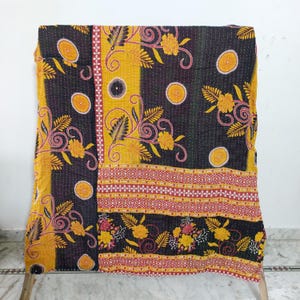 May include: A rectangular quilt featuring a dark charcoal background with a vibrant yellow floral and circular pattern. The textile displays intricate kantha stitching throughout, with a horizontal band of red and white geometric motifs.