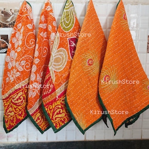 Może przedstawiać: Cztery pomarańczowe i białe ręczniki do herbaty w stylu kantha z zielonym wykończeniem. Ręczniki mają różne wzory, w tym kwiatowe, paisley i geometryczne.