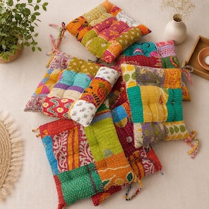 May include: A collection of square floor cushions featuring a patchwork design made from various colorful fabrics with intricate patterns. Each cushion is tufted with visible stitching and includes fabric ties at the corners for securing.