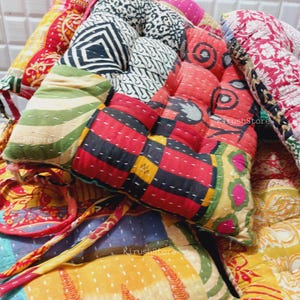 May include: A set of colorful patchwork cushion covers with intricate stitching and a variety of patterns. The cushions are made from recycled saris and are perfect for adding a touch of bohemian style to any room.
