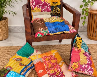 Peut inclure: Un ensemble de quatre coussins de sol carrés présentant un motif patchwork composé de divers tissus colorés aux motifs complexes. Chaque coussin est capitonné et affiche un mélange d'imprimés floraux et géométriques jaunes, bleus, roses et verts.