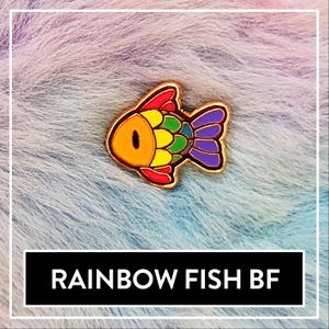 May include: A brightly coloured fish-shaped enamel pin with a gold border. The fish is filled with rainbow colours: red, orange, yellow, green, and purple. The text "RAINBOW FISH BF" is displayed in a black rectangle.