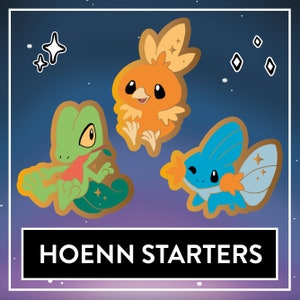 Op de afbeelding: Drie cartoon Pokémon-starter uit de Hoenn-regio. De personages zijn Treecko, Torchic en Mudkip. De personages zijn afgebeeld in een gouden omtrek tegen een donkerblauwe achtergrond met sterren.