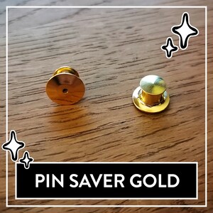 May include: Two gold-colored pin savers, one with a flat back and the other with a round top. The text "PIN SAVER GOLD" is printed on a black banner.