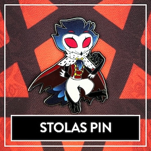 May include: A black and blue enamel pin featuring a cartoon character with red eyes, a crown, and a cape. The character is standing with one leg raised and has a mischievous expression. The pin says "Stolas Pin" at the bottom.