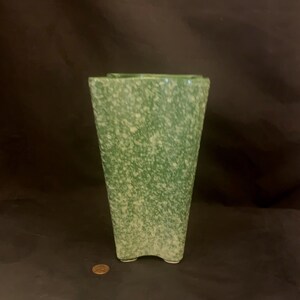 May include: A green ceramic vase with a speckled white glaze. The vase has a square base and a rectangular body.