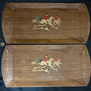 May include: Two wooden serving trays with a woodgrain finish. Each tray features a painted scene of riders on horseback with hounds chasing a fox. The trays are rectangular with rounded corners.