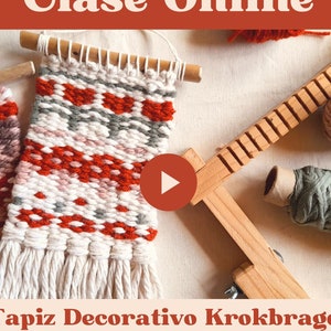 May include: A close-up of a wooden loom with two finished wall hangings and yarn in various colours. The text "Clase Online" is at the top of the image. The text "Tapiz Decorativo Krokbradg" is below the loom. The text "Video + Guía" is at the bottom of the image.
