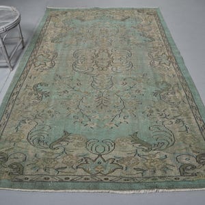 May include: A vintage rug with a faded teal background and a floral pattern in shades of brown and beige.