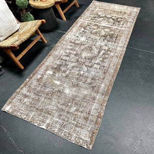 May include: A vintage-style runner rug with a faded brown and white pattern. The rug has a distressed look and is perfect for adding a touch of bohemian style to any room.