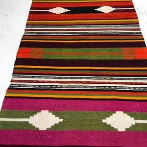 May include: A colorful striped rug with a geometric pattern. The rug is made of wool and has a traditional design. It is perfect for adding a touch of color and style to any room.