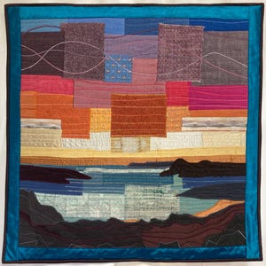 Puede incluir: Una colorida obra de arte textil con un diseño de paisaje. La obra presenta un patchwork de varias telas en tonos azules, naranjas, rosas y morados. La pieza está enmarcada con un borde turquesa.