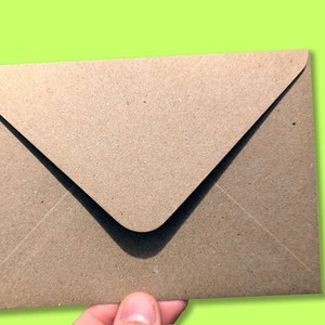 May include: A brown paper envelope with a white flap. The envelope is made of recycled paper and has a textured surface.