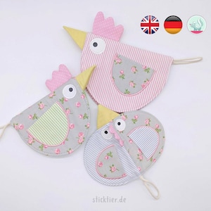 Può includere: Tre borse di stoffa a forma di pollo con un motivo floreale e una tasca a righe. Le borse hanno un anello per appendere e sono rosa, verde e blu.