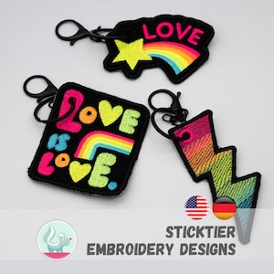 Könnte beinhalten: Drei bestickte Schlüsselanhänger mit schwarzen Kunststoffverschlüssen. Einer ist ein Stern mit Regenbogen und dem Wort LOVE. Einer ist ein quadratischer Aufnäher mit der Aufschrift LOVE IS LOVE und Regenbogen. Einer ist ein Blitz mit Regenbogenverlauf.
