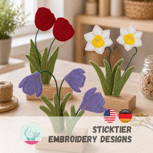 May include: Embroidered felt flowers in red tulips, purple bellflowers, and white daffodils with yellow centers. The flowers are mounted on wooden blocks with green stems and leaves. The image includes the text "STICKTIER EMBROIDERY DESIGNS".