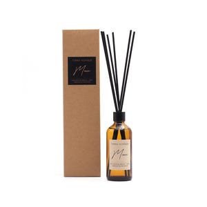 May include: An amber glass aromatherapy diffuser bottle with black reeds and a matching cardboard box. The bottle has a black cap and a label with the text "Terra Nomade" and "Moni". The box also has the same label.