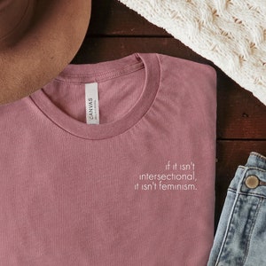 Puede incluir: Una camiseta color malva con el texto "If it isn't intersectional, it isn't feminism." impreso en la parte delantera.