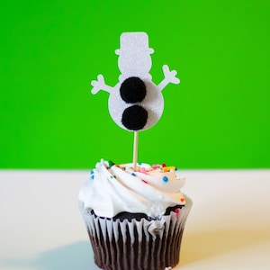 May include: A chocolate cupcake with white icing and colourful sprinkles, topped with a glittery snowman decoration. The snowman has a black top hat and two black pom-pom eyes.