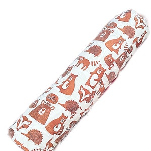 May include: A white and brown cylindrical pillow with a repeating pattern of bears, hedgehogs, and other woodland creatures. The pillow has the word "hello" printed on it.
