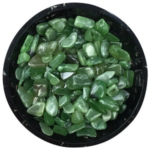 May include: A bowl filled with green jade tumbled stones. The stones are smooth and polished, and they have a variety of shapes and sizes.