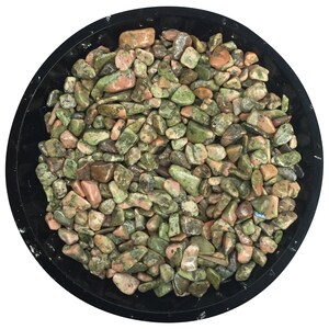 Pode incluir: Uma tigela cheia de pedras polidas verdes, rosa e marrons. As pedras são lisas e polidas.