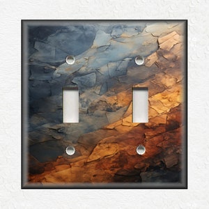 May include: A double light switch plate with a colorful abstract design featuring shades of blue, brown, and orange. The design resembles a rocky landscape.