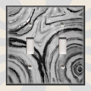 May include: A black and white marble-patterned light switch cover plate. The pattern resembles a swirling, abstract design.