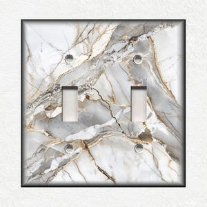 May include: A white and gold marble light switch cover with two toggle switches.