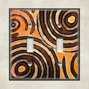 May include: A light switch plate with a decorative design featuring swirling orange, brown, and white patterns.