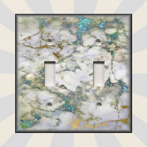 May include: A white light switch cover with a marble pattern featuring blue and gold accents. The switch cover has two toggle switches.