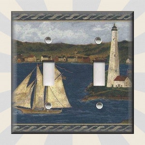May include: A decorative double light switch cover featuring a nautical scene. The artwork depicts a sailboat on the water, a lighthouse, and a coastal town. The color palette includes blues, greens, and beige tones, with a textured border.