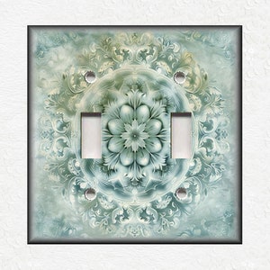 May include: A light blue and green decorative light switch cover with a mandala design.