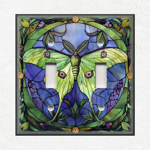 May include: A stained glass light switch cover featuring a green and yellow luna moth with blue and purple accents. The moth is surrounded by a floral design.